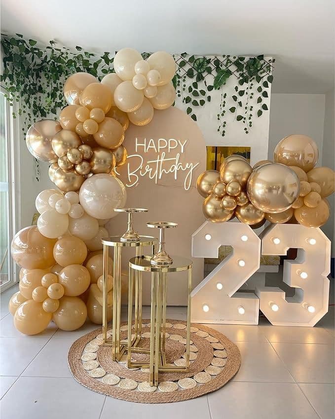 Gold and cream balloon display beside illuminated marquee numbers reading 23