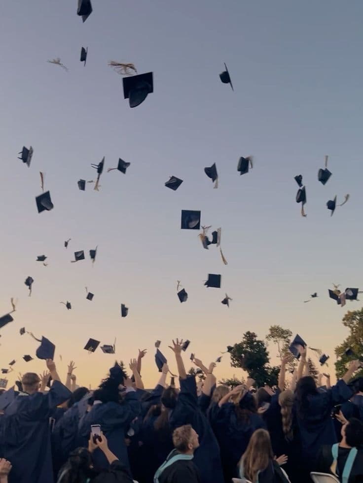 Graduates throwing their caps into the air at dusk